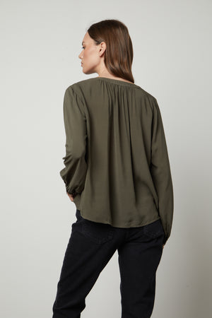 The back view of a woman wearing jeans and a Velvet by Graham & Spencer POSIE SPLIT NECK BLOUSE.