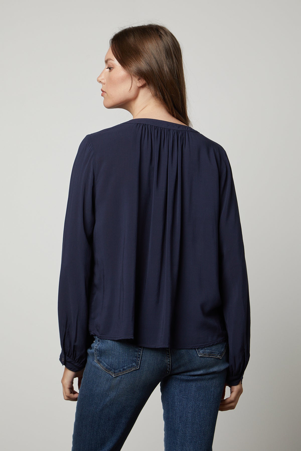 The back view of a woman wearing jeans and a POSIE SPLIT NECK BLOUSE made by Velvet by Graham & Spencer.-26834994200769