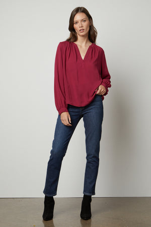 The model is wearing jeans and a Velvet by Graham & Spencer POSIE SPLIT NECK BLOUSE.