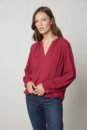 A model wearing a Velvet by Graham & Spencer POSIE SPLIT NECK BLOUSE and jeans.