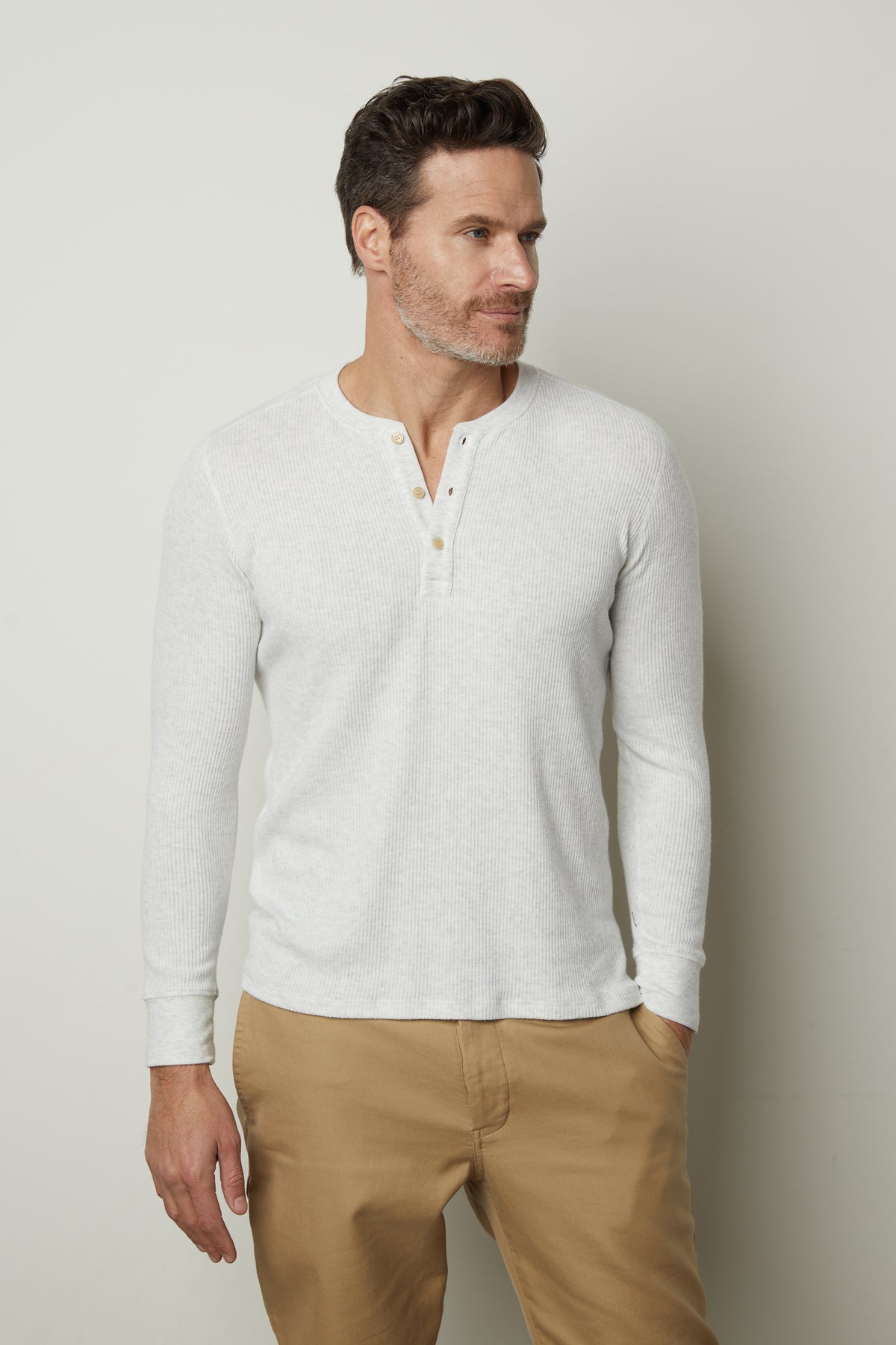   A man wearing a Velvet by Graham & Spencer Anderson Rib Knit Henley shirt and khaki pants. 