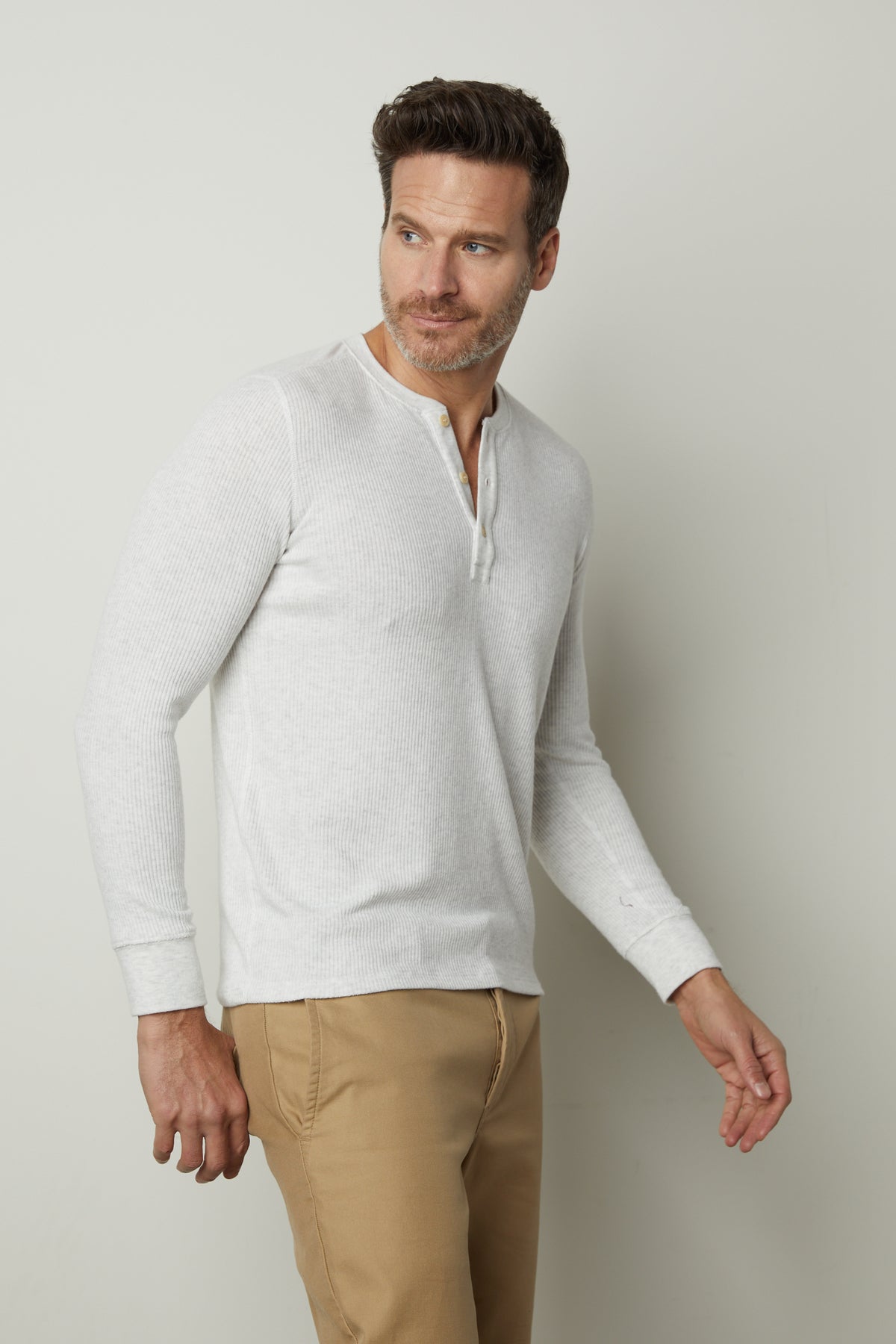   A man wearing a Velvet by Graham & Spencer Anderson Rib Knit Henley shirt and tan pants. 