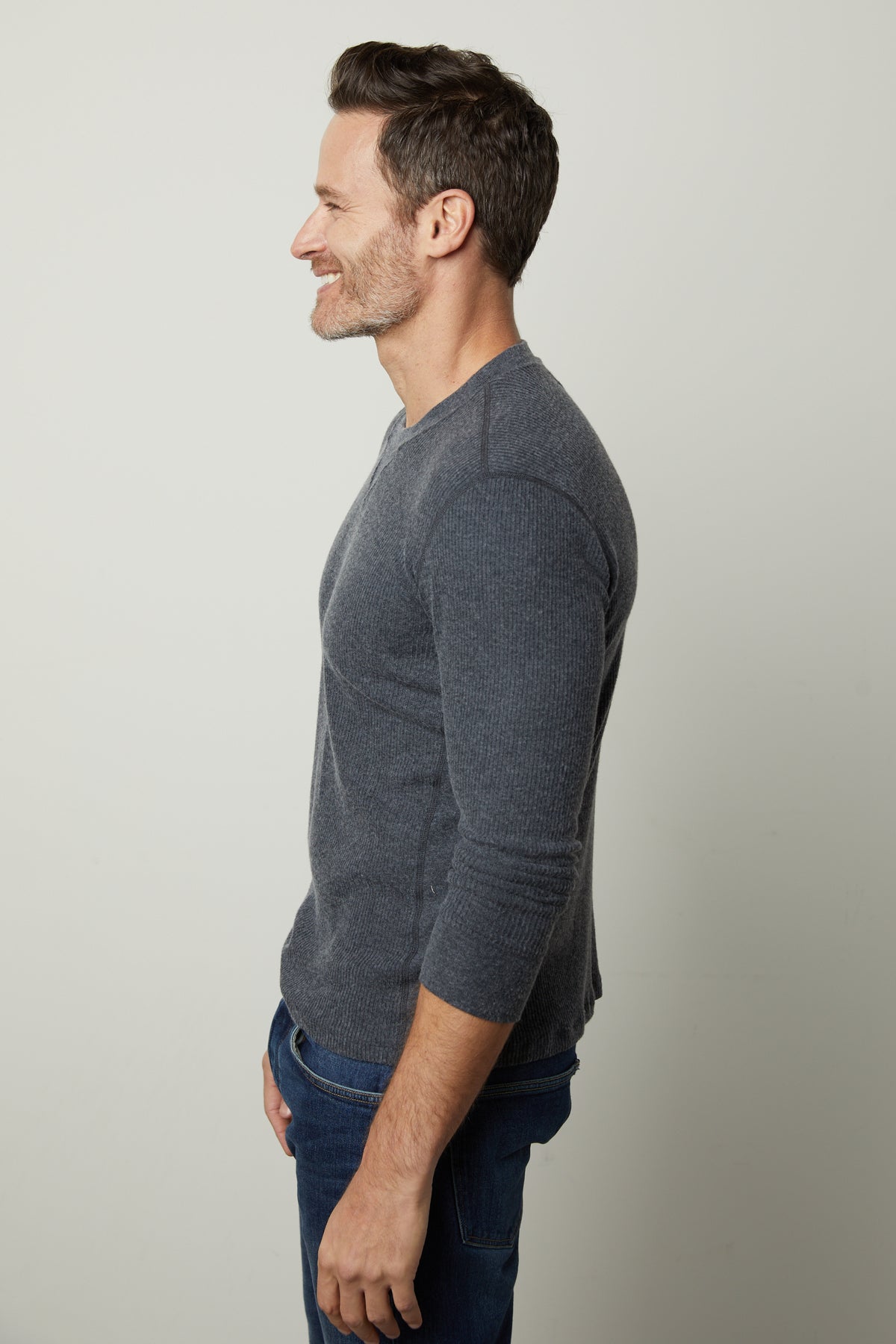 A man wearing jeans and a grey Velvet by Graham & Spencer AUGUSTUS RIB KNIT CREW sweater.-26905806700737