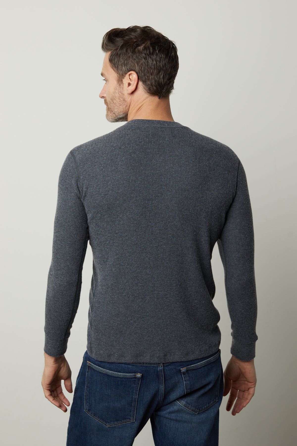   The back view of a man wearing Velvet by Graham & Spencer's Augustus Rib Knit Crew jeans and a grey sweater. 