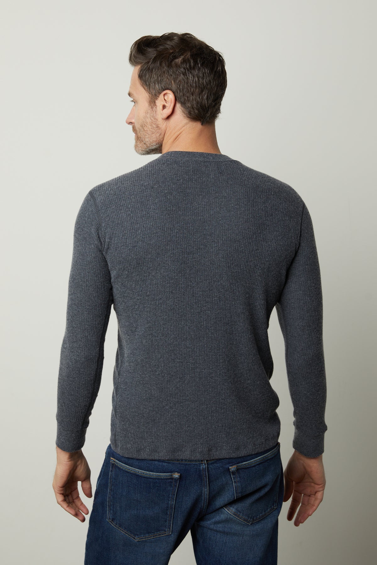 The back view of a man wearing Velvet by Graham & Spencer's Augustus Rib Knit Crew jeans and a grey sweater.-26905806733505