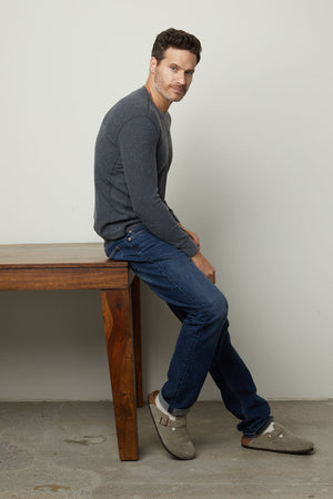 A man enjoying unparalleled comfort while sitting on an AUGUSTUS RIB KNIT CREW by Velvet by Graham & Spencer.