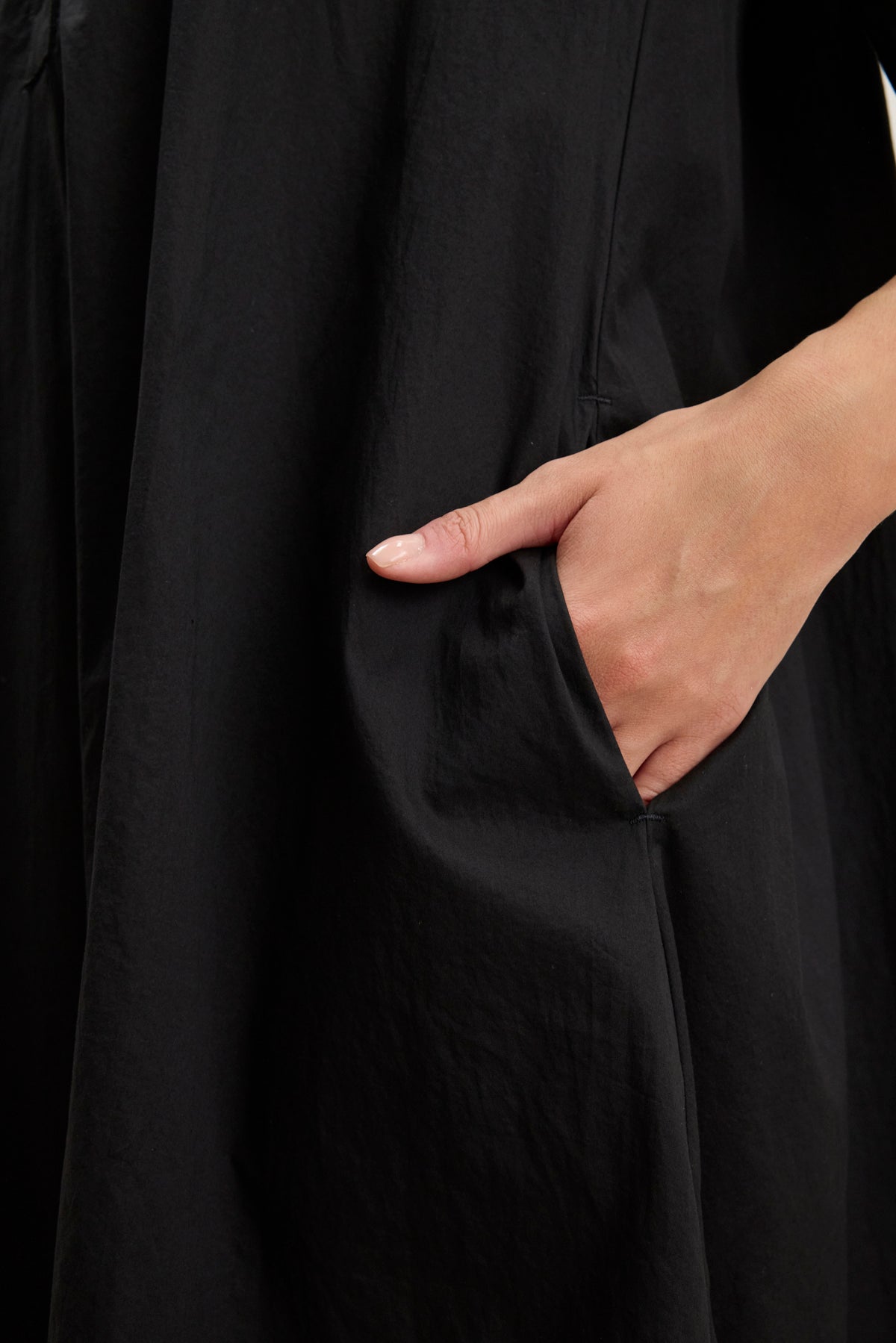 A close-up of a hand placed inside the side seam pocket of the loose-fitting black cotton poplin DRIANA DRESS by Velvet by Graham & Spencer.-39145480683713
