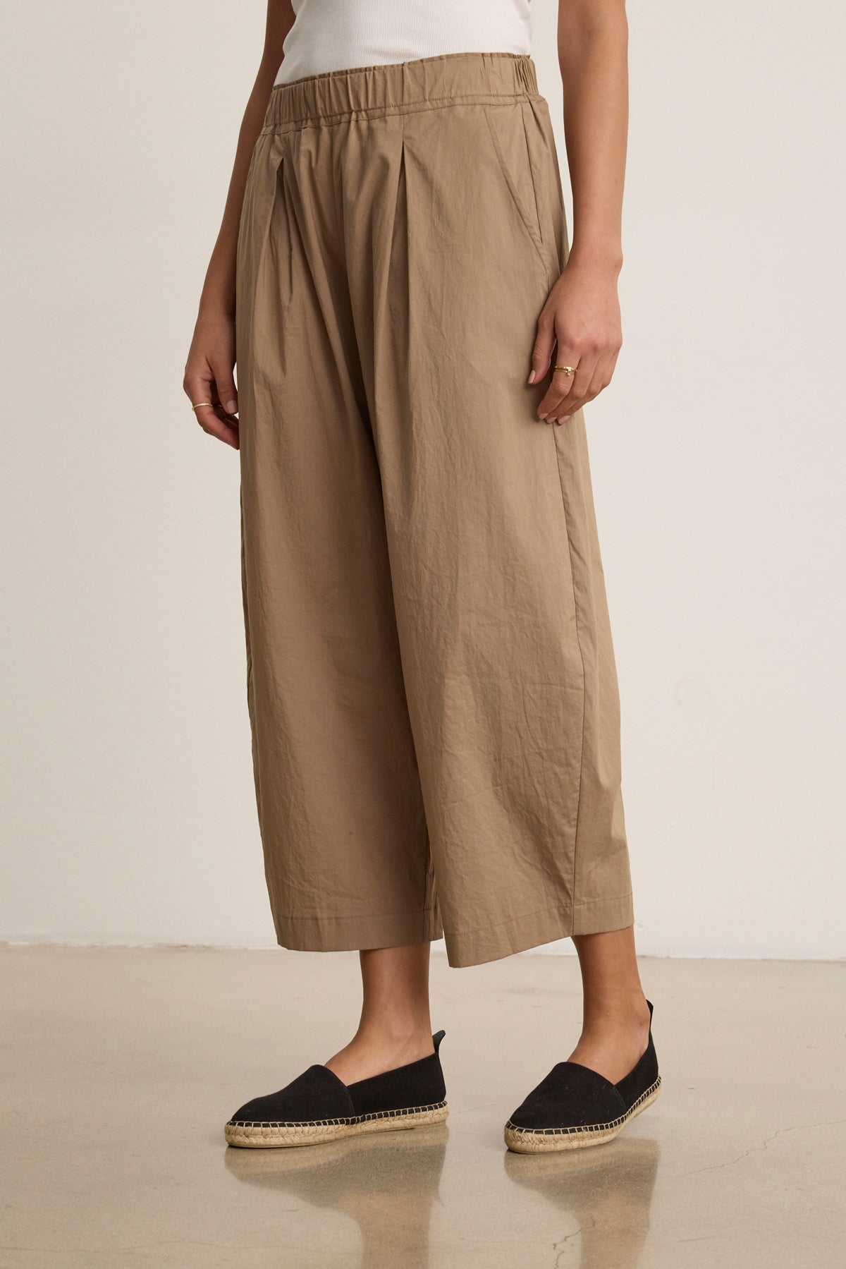 A person wears the SOPHIA PANT by Velvet by Graham & Spencer—beige cotton poplin cropped balloon pants—paired with black espadrilles, standing against a plain background and highlighting a relaxed silhouette.-40030496161985