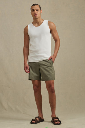 A man stands against a neutral background wearing the CARLOS TANK by Velvet by Graham & Spencer, paired with olive green shorts and brown sandals.