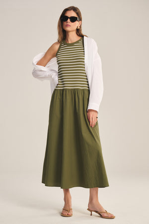 A woman wearing the ROMINA DRESS by Velvet by Graham & Spencer stands with one hand on her hip against a neutral background.