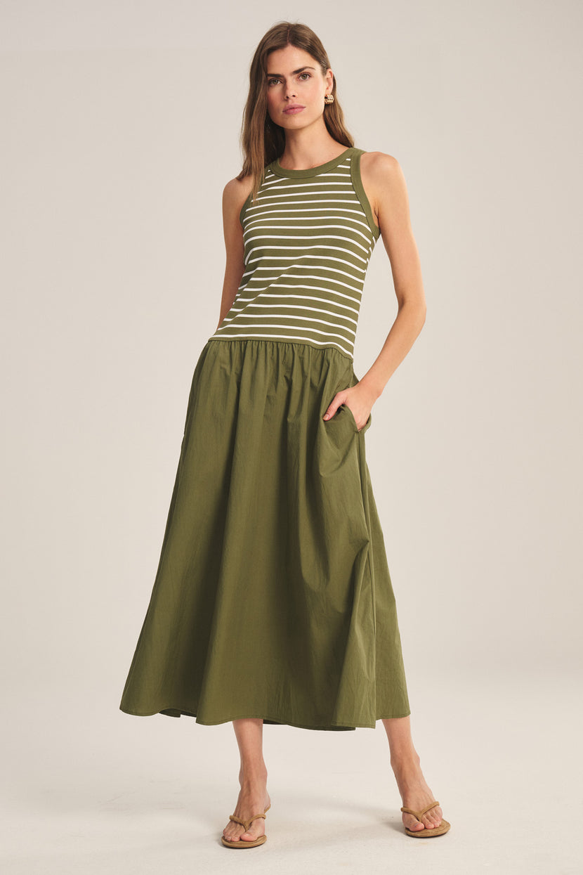 A woman models the ROMINA DRESS by Velvet by Graham & Spencer, a sleeveless green and white striped cotton rib dress paired with a matching olive green ankle-length skirt and sandals, set against a neutral background.