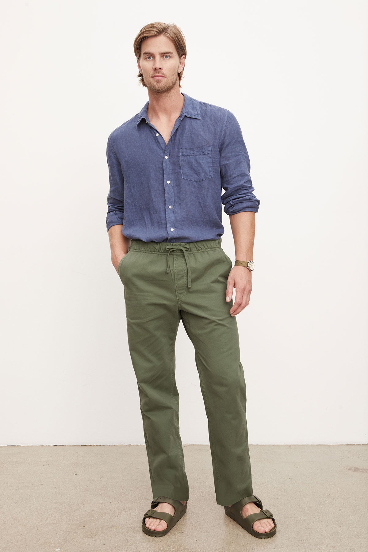   Man in a blue shirt and green BRANSON PANT by Velvet by Graham & Spencer with an elastic drawstring waist posing for a photo. 