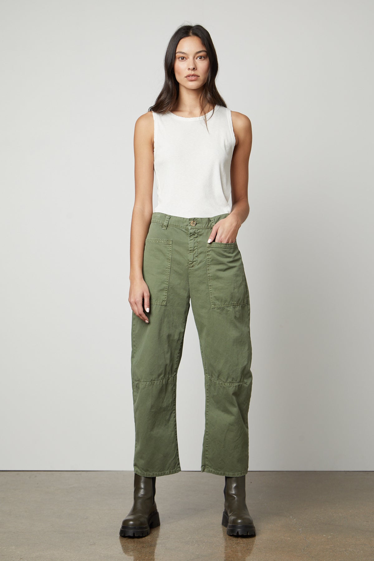A woman wearing a white top and green pants made of Velvet by Graham & Spencer's BRYLIE SANDED TWILL UTILITY PANT with patch pockets.-36118556541121