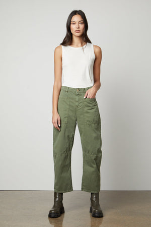 A woman wearing a white top and green pants made of Velvet by Graham & Spencer's BRYLIE SANDED TWILL UTILITY PANT with patch pockets.