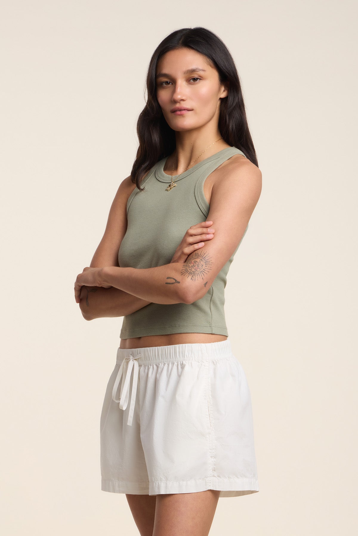 A woman stands with arms crossed, wearing the SARI TANK TOP by Velvet by Graham & Spencer in green and white shorts against a plain background.-41645099385025