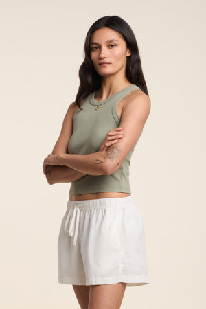 A woman stands with arms crossed, wearing the SARI TANK TOP by Velvet by Graham & Spencer in green and white shorts against a plain background.