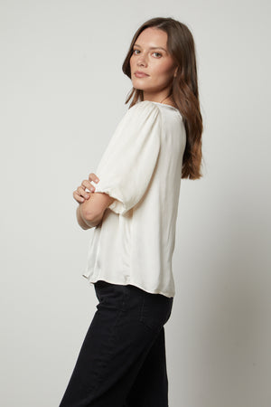 The model is wearing a DESI SATIN PUFF SLEEVE TOP by Velvet by Graham & Spencer and relaxed fit jeans.