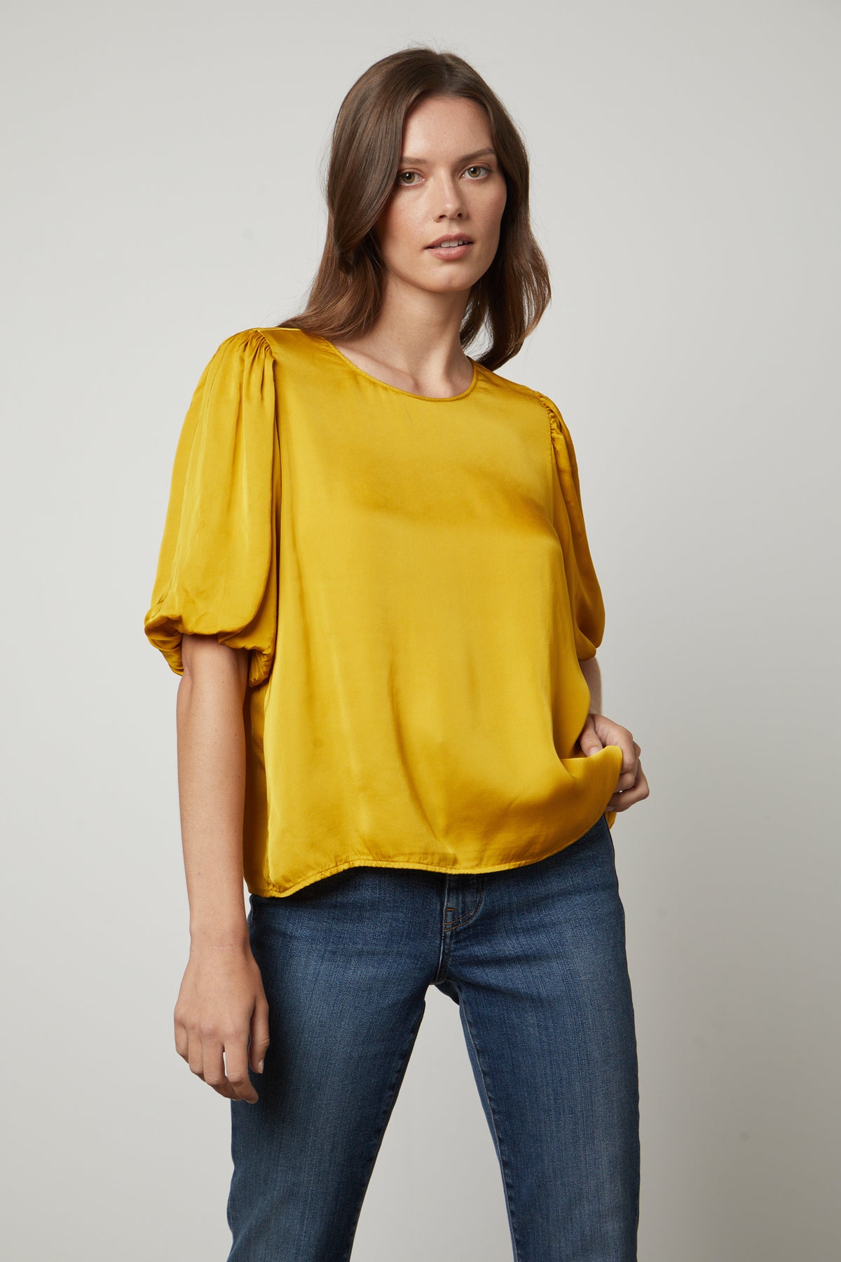 The model is wearing a yellow DESI SATIN PUFF SLEEVE TOP by Velvet by Graham & Spencer.-35656169423041