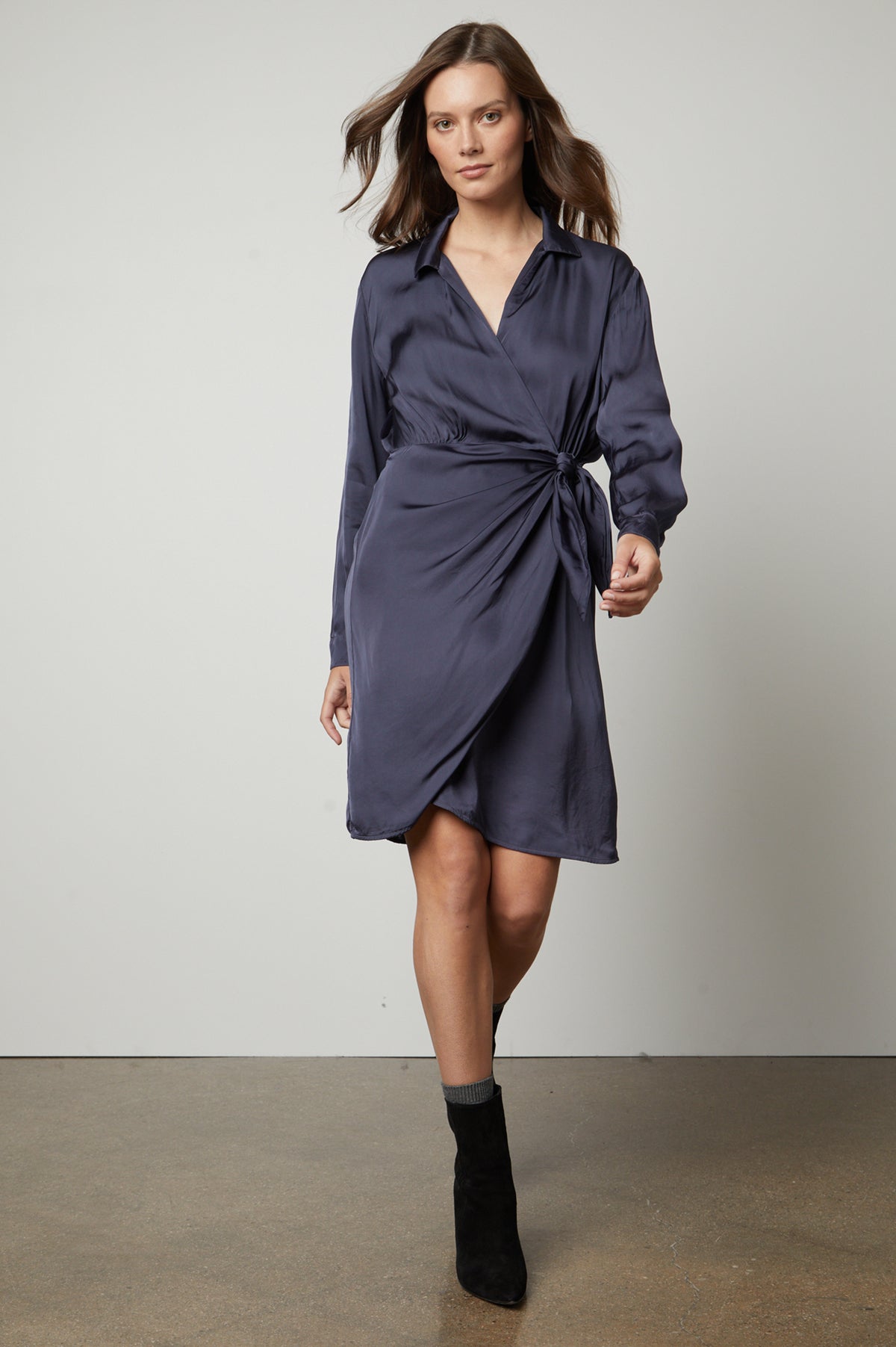 The model is wearing a Velvet by Graham & Spencer JUNI wrap dress with a satin viscose sheen.-35656155234497