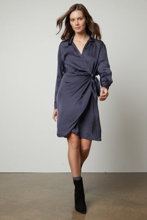 The model is wearing a Velvet by Graham & Spencer JUNI wrap dress with a satin viscose sheen.