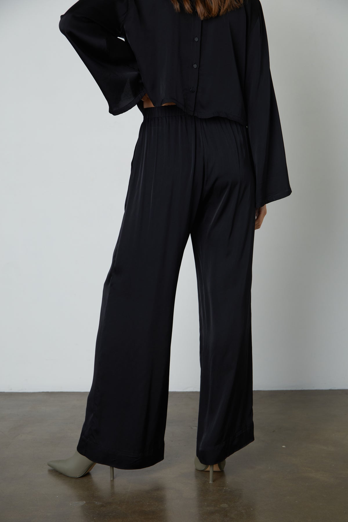   The back view of a woman wearing Velvet by Graham & Spencer LIVI SATIN VISCOSE WIDE LEG PANT with slash pockets. 
