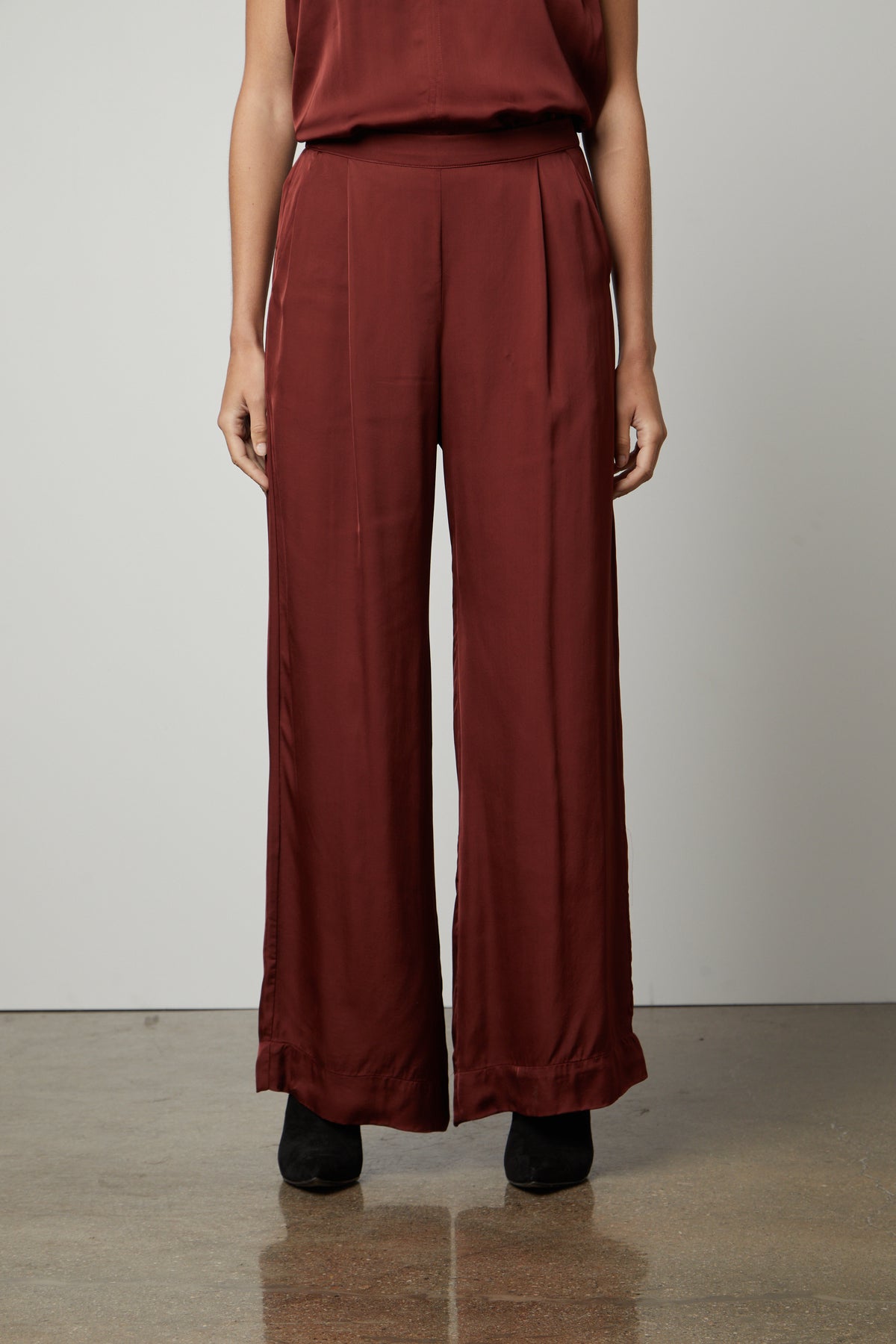 A woman wearing a Velvet by Graham & Spencer LIVI SATIN VISCOSE WIDE LEG PANT with an elastic waistline and slash pockets.-35655937786049