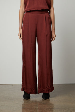 A woman wearing a Velvet by Graham & Spencer LIVI SATIN VISCOSE WIDE LEG PANT with an elastic waistline and slash pockets.
