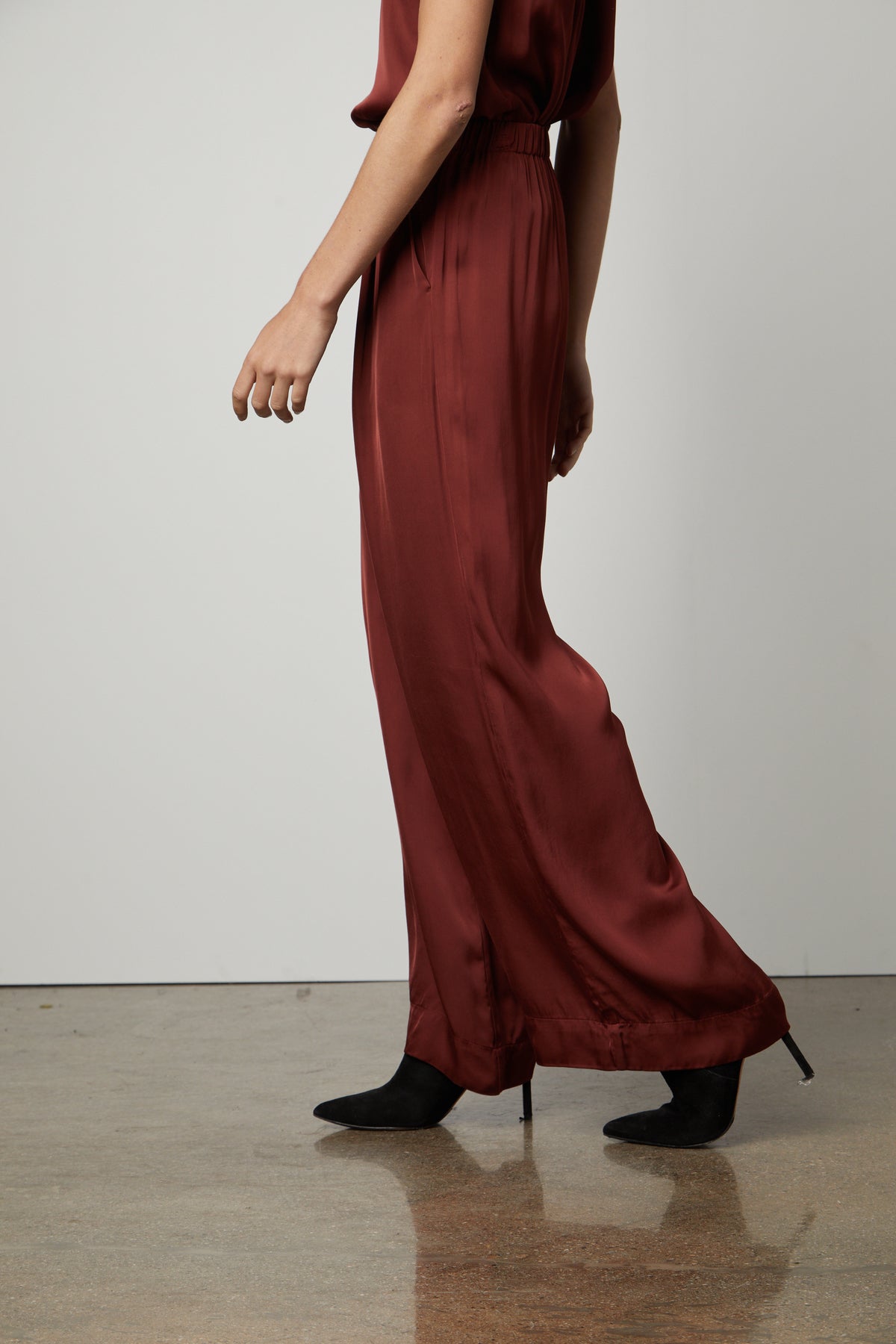 The model is wearing Velvet by Graham & Spencer's LIVI SATIN VISCOSE WIDE LEG PANT with an elastic waistline and slash pockets.-35655937818817