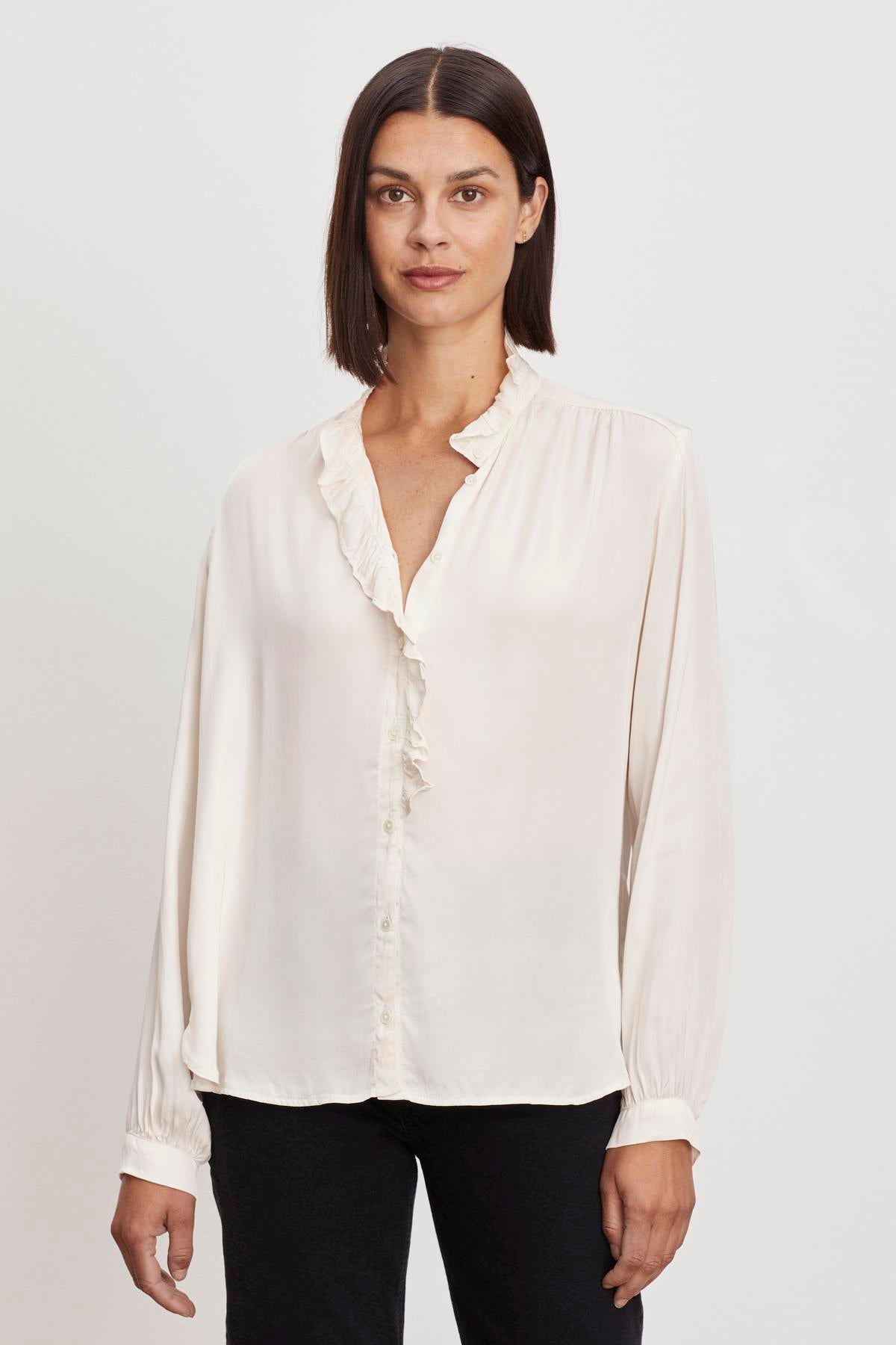 A woman in a Velvet by Graham & Spencer ALI BUTTON FRONT BLOUSE with a ruffle neckline.-36220810494145
