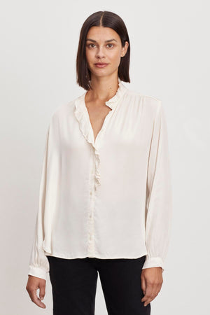 A woman in a Velvet by Graham & Spencer ALI BUTTON FRONT BLOUSE with a ruffle neckline.