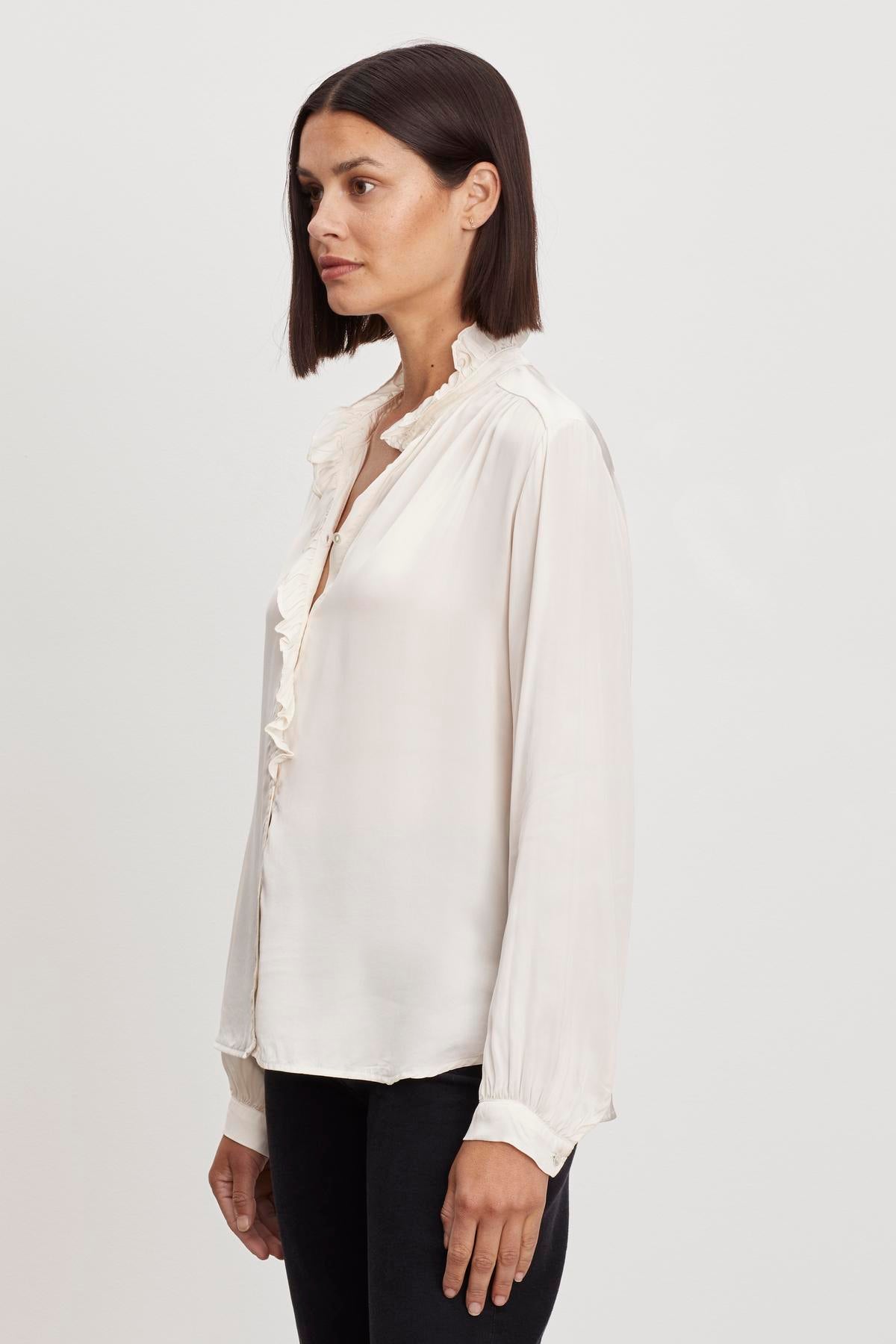   The model is wearing a Velvet by Graham & Spencer ALI BUTTON FRONT BLOUSE with ruffles on the neckline. 