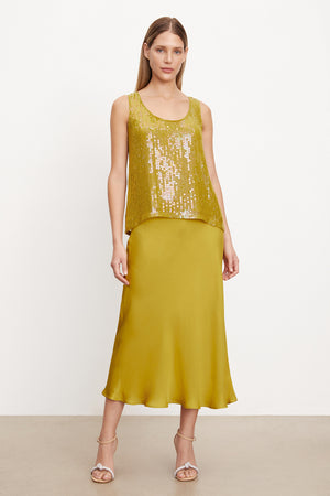A woman wearing a yellow Velvet by Graham & Spencer BEHATI sequin tank top with scoop neckline and midi skirt, featuring a-line silhouette.