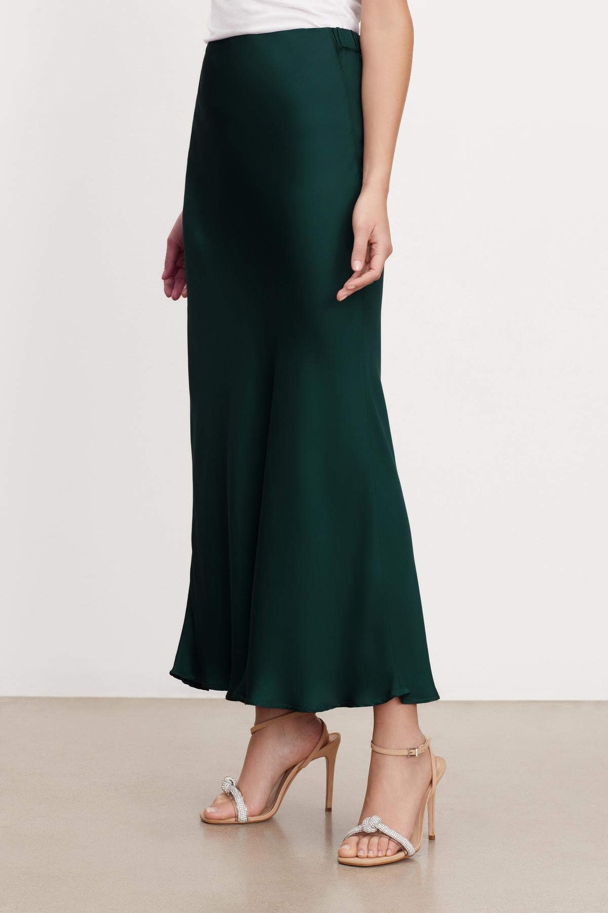 A woman wearing a flattering fit Velvet by Graham & Spencer green satin CADENCE SATIN MAXI SKIRT made of viscose fabric.-35654454771905