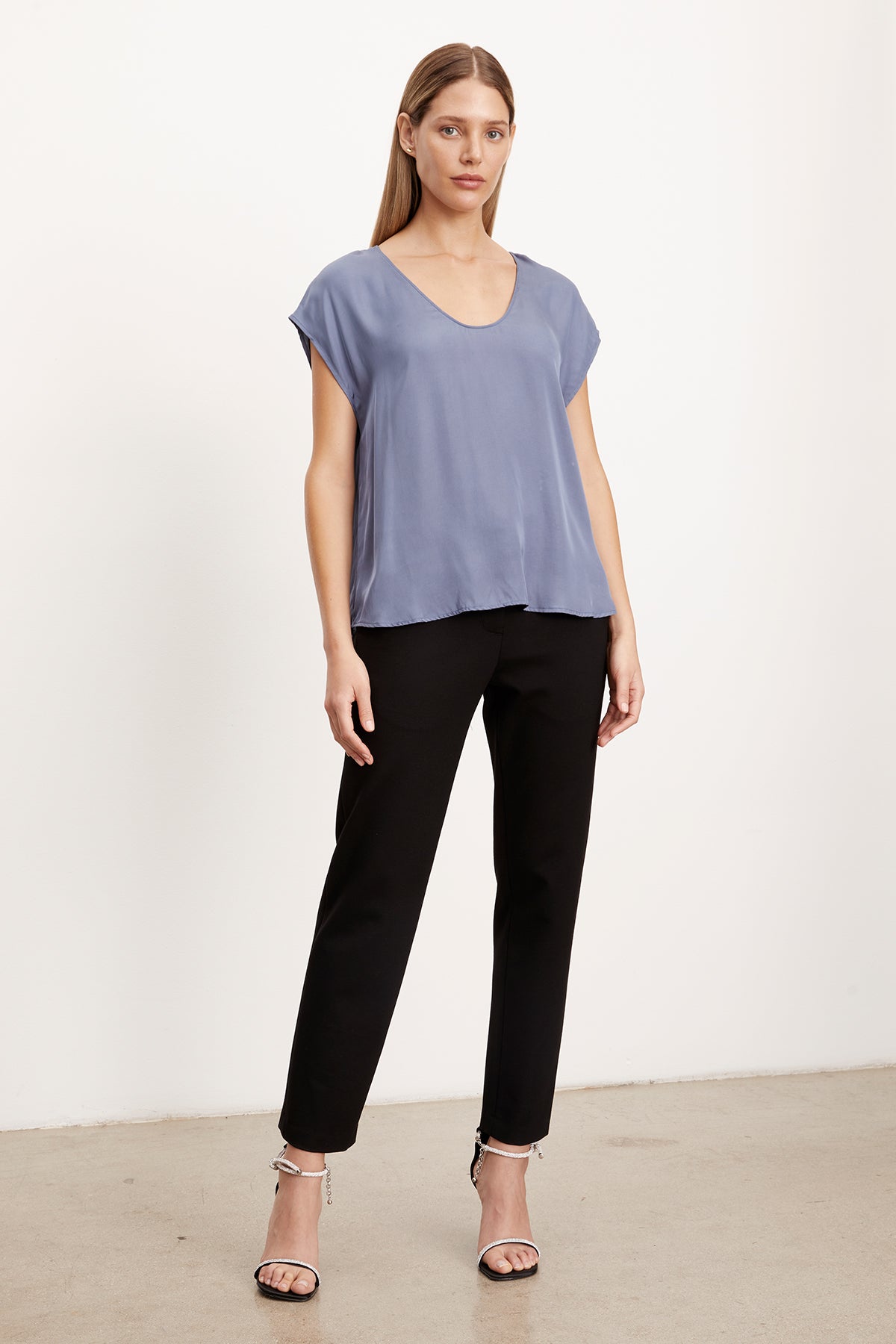   The model is wearing a blue v-neck top and Velvet by Graham & Spencer JAY PONTI STRAIGHT LEG PANT. 