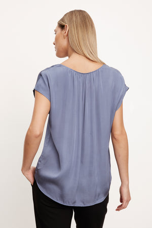 The back view of a woman wearing a KALI SATIN SCOOP NECK TOP by Velvet by Graham & Spencer.