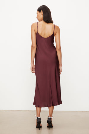 The versatile slip dress, the POPPY SATIN SLIP DRESS by Velvet by Graham & Spencer, features adjustable straps and showcases the back view of a woman wearing a burgundy slip dress.