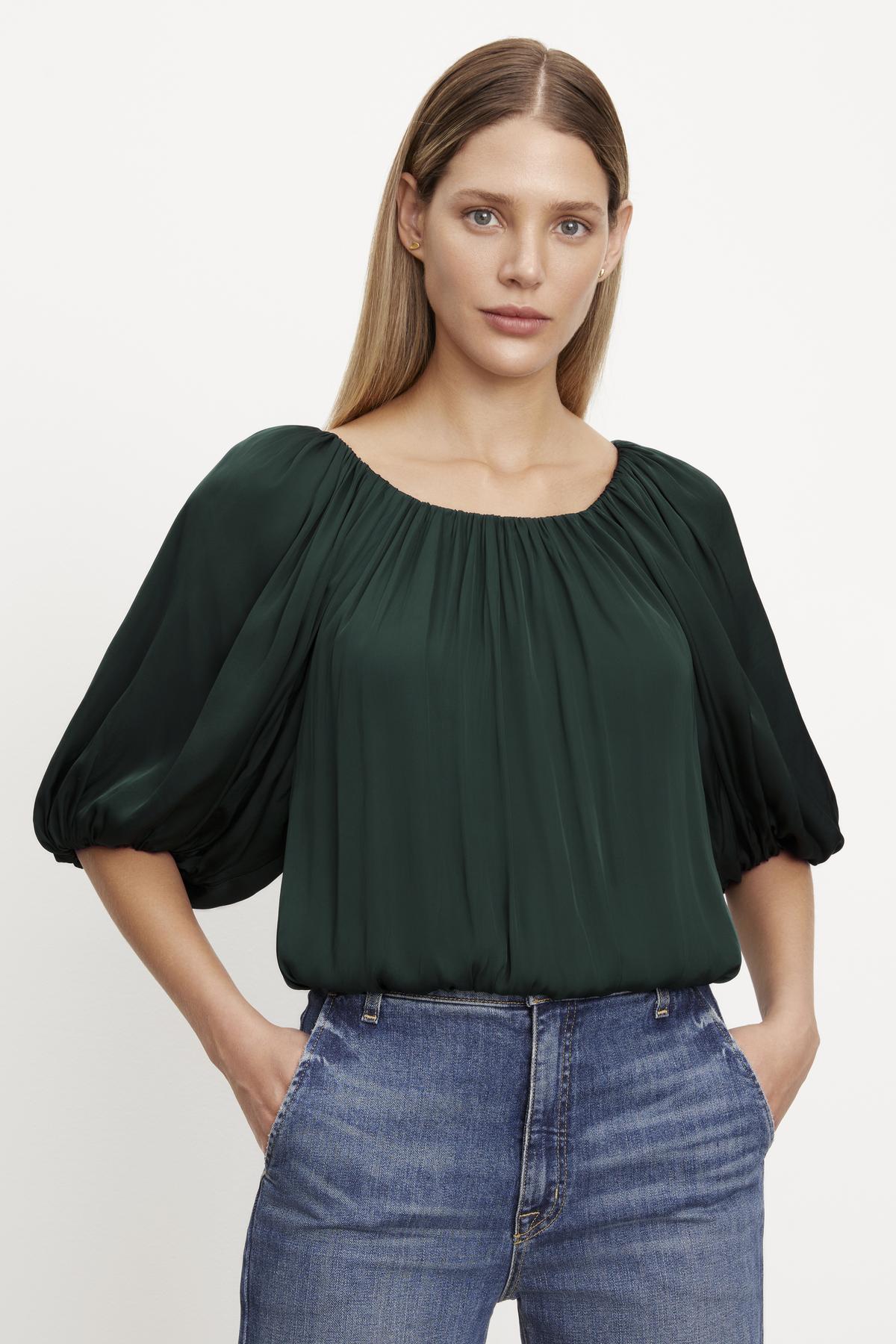   The model is wearing a green cropped TAMI SATIN PUFF SLEEVE TOP by Velvet by Graham & Spencer. 
