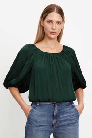 The model is wearing a green cropped TAMI SATIN PUFF SLEEVE TOP by Velvet by Graham & Spencer.