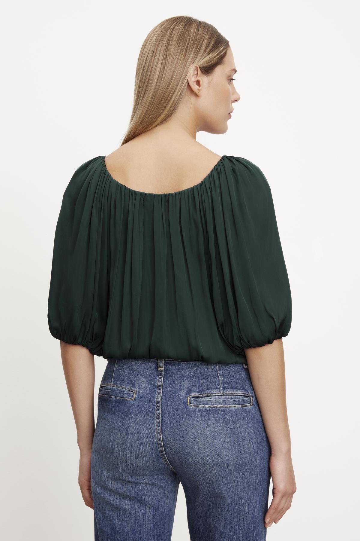 The back view of a woman wearing jeans and a Velvet by Graham & Spencer TAMI SATIN PUFF SLEEVE TOP.-35654471221441