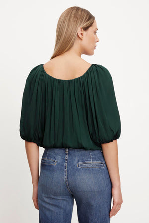 The back view of a woman wearing jeans and a Velvet by Graham & Spencer TAMI SATIN PUFF SLEEVE TOP.