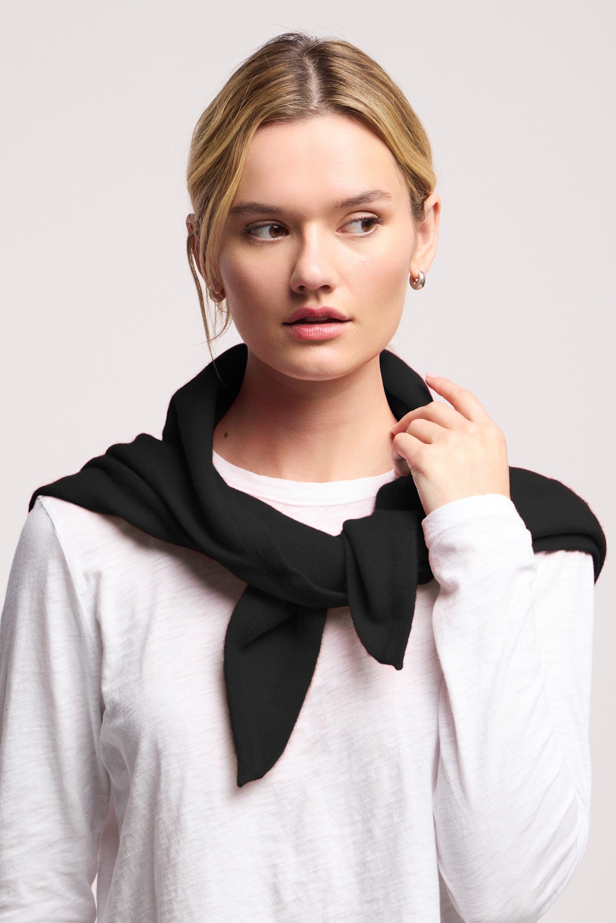 A woman wears a white long-sleeve shirt and has the LARGE TRIANGLE BANDANA BY 40 COLORI from 40 Colori draped over her shoulders, looking to the side against a plain backdrop.