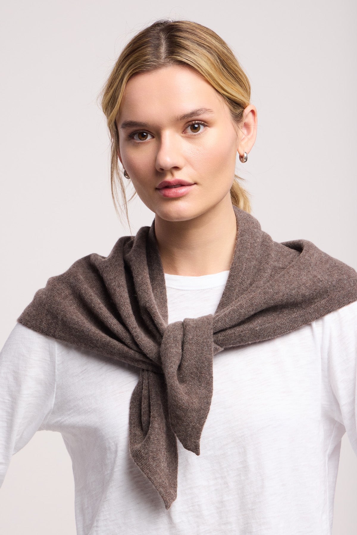 A person wears the LARGE TRIANGLE BANDANA BY 40 COLORI from 40 Colori, elegantly styled over a white shirt and brown sweater, gazing at the camera against a plain backdrop.-40459534926017