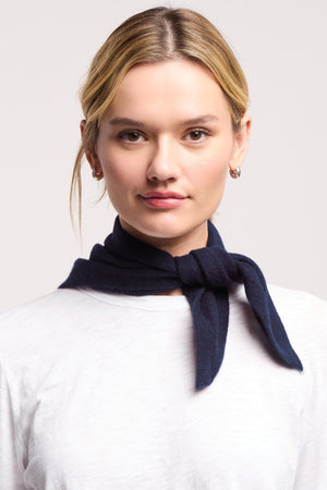 A person wearing a white shirt and the SMALL TRIANGLE BANDANA BY 40 COLORI from 40 Colori, tied around their neck, faces the camera against a plain background.