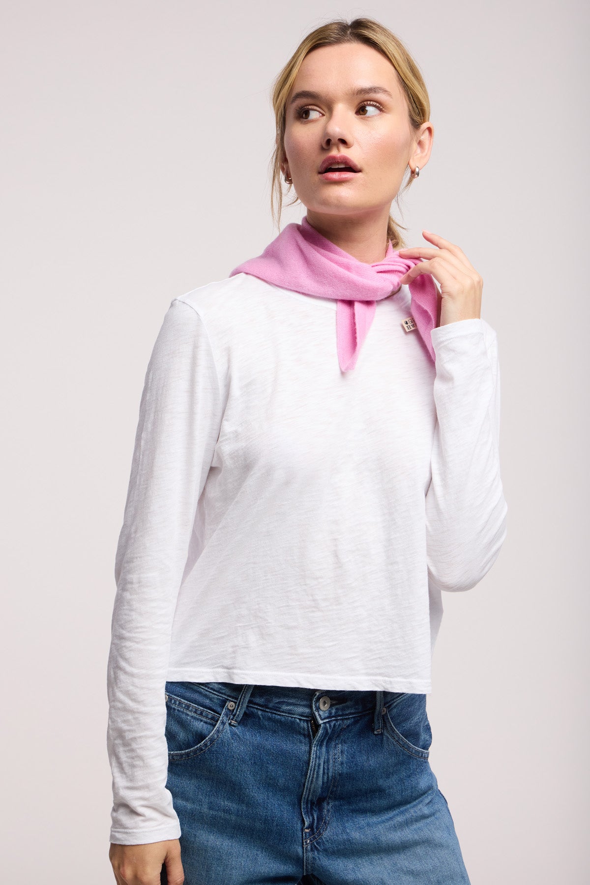 A person wearing the SMALL TRIANGLE BANDANA BY 40 COLORI, styled around their neck, looks slightly to the side against a plain background.