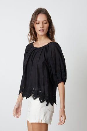 Woman wearing a Velvet by Graham & Spencer ABIGAIL SCHIFFLI EYELET BLOUSE with embroidered details.