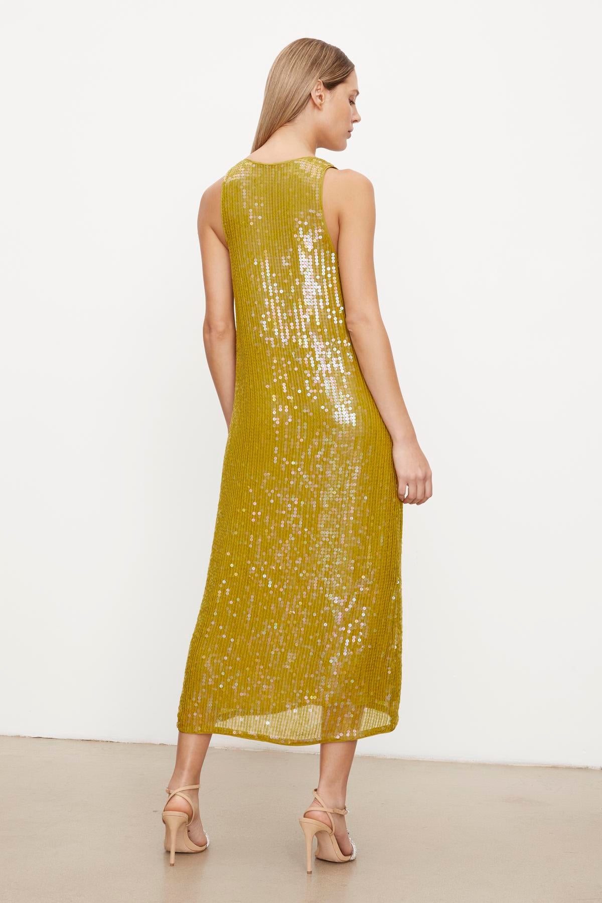   Woman modeling a sleeveless, mustard yellow Velvet by Graham & Spencer ALENA SEQUIN TANK DRESS with a high neckline, viewed from the back. 