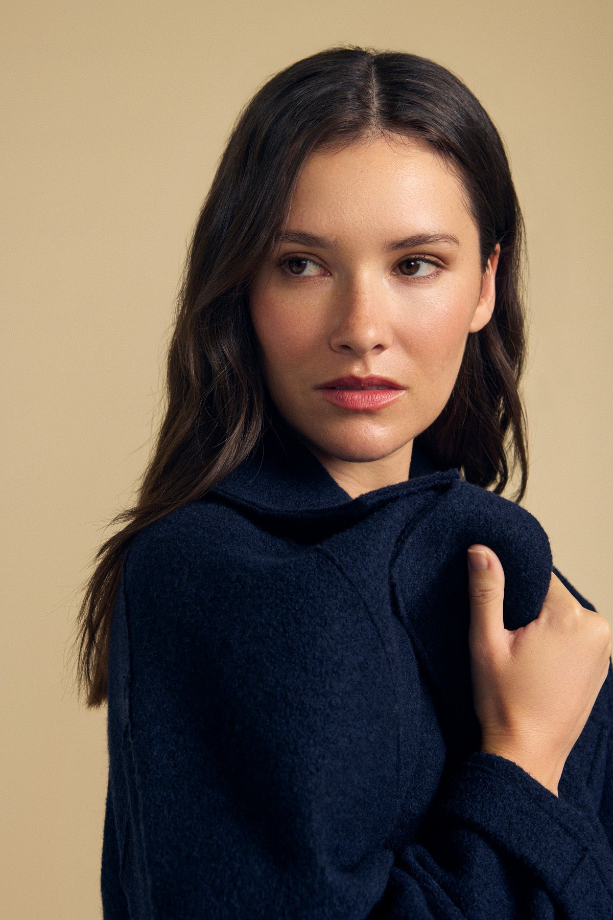 Woman with long brown hair wearing the ABBY BLAZER by Velvet by Graham & Spencer—an oversized navy wool blazer—looking to the side against a plain beige background. Perfect for everyday layering.