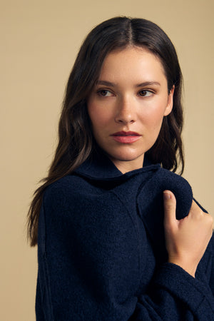 Woman with long brown hair wearing the ABBY BLAZER by Velvet by Graham & Spencer—an oversized navy wool blazer—looking to the side against a plain beige background. Perfect for everyday layering.