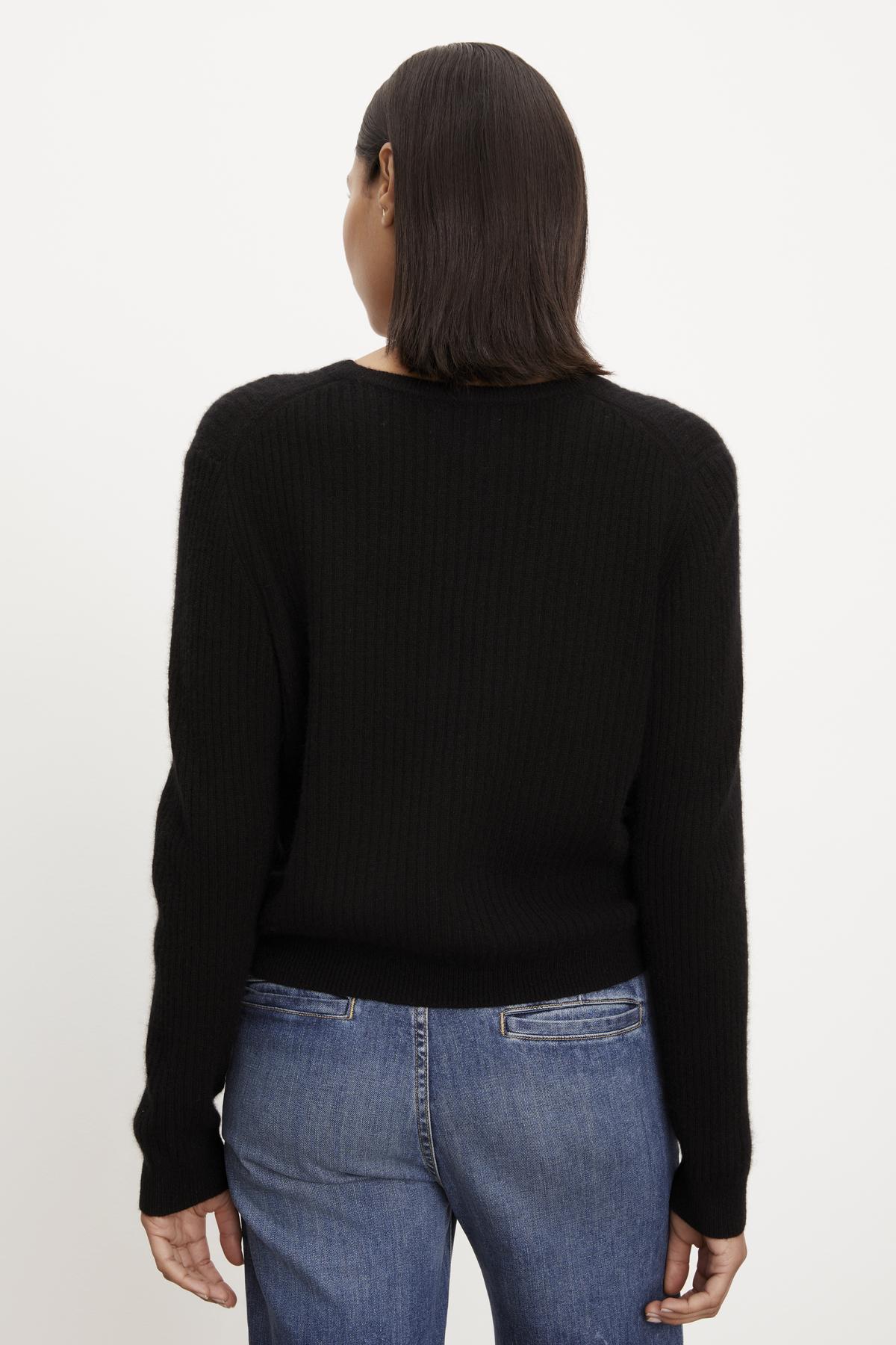   The back view of a person wearing a Velvet by Graham & Spencer CORALIE CASHMERE CARDIGAN and jeans. 