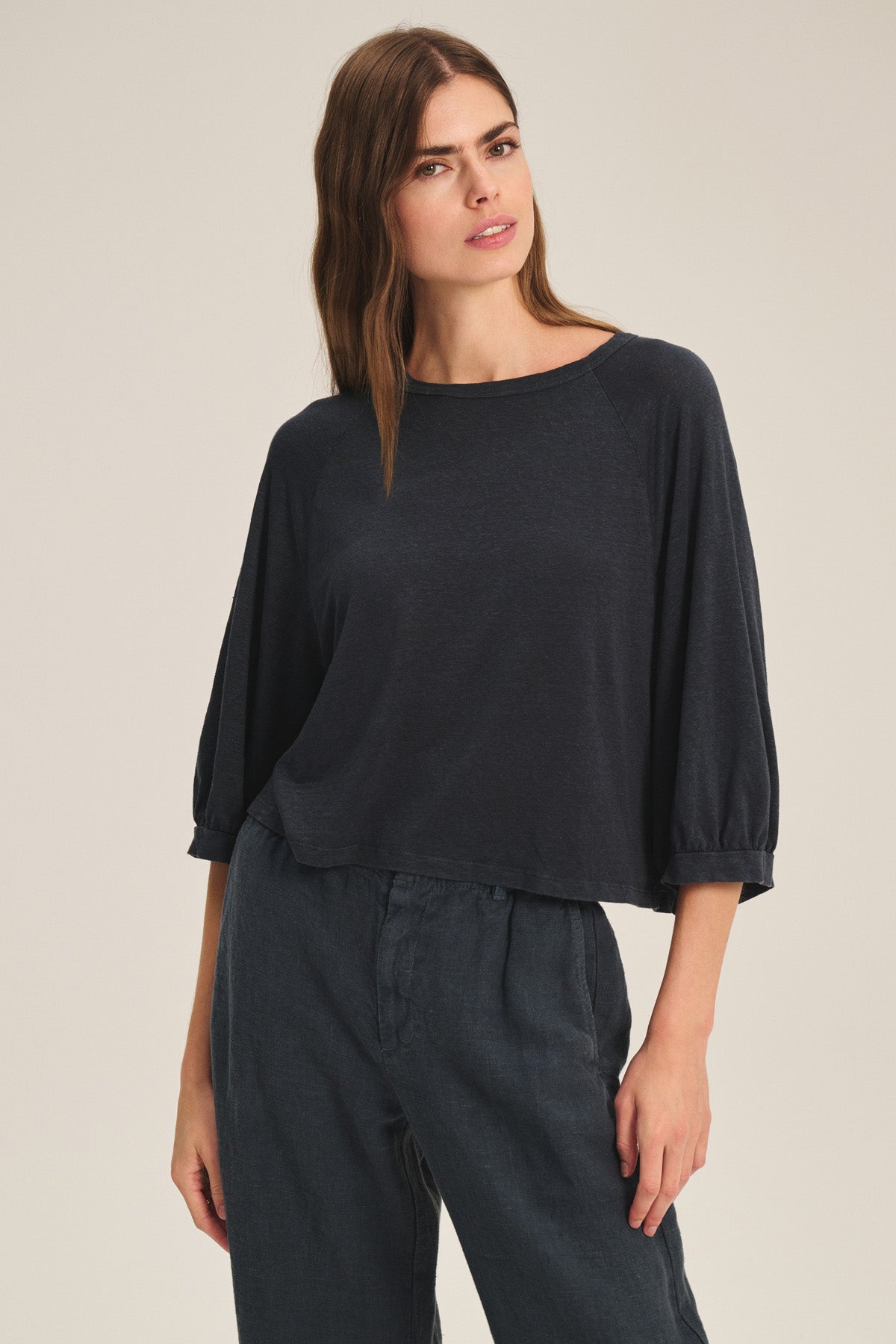 A woman wears the SHELLY TEE by Velvet by Graham & Spencer, a loose-fitting, dark, lightweight linen knit top paired with matching wide-leg pants, standing against a plain light background.